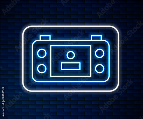 Glowing neon line Portable video game console icon isolated on brick wall background. Handheld console gaming. Vector