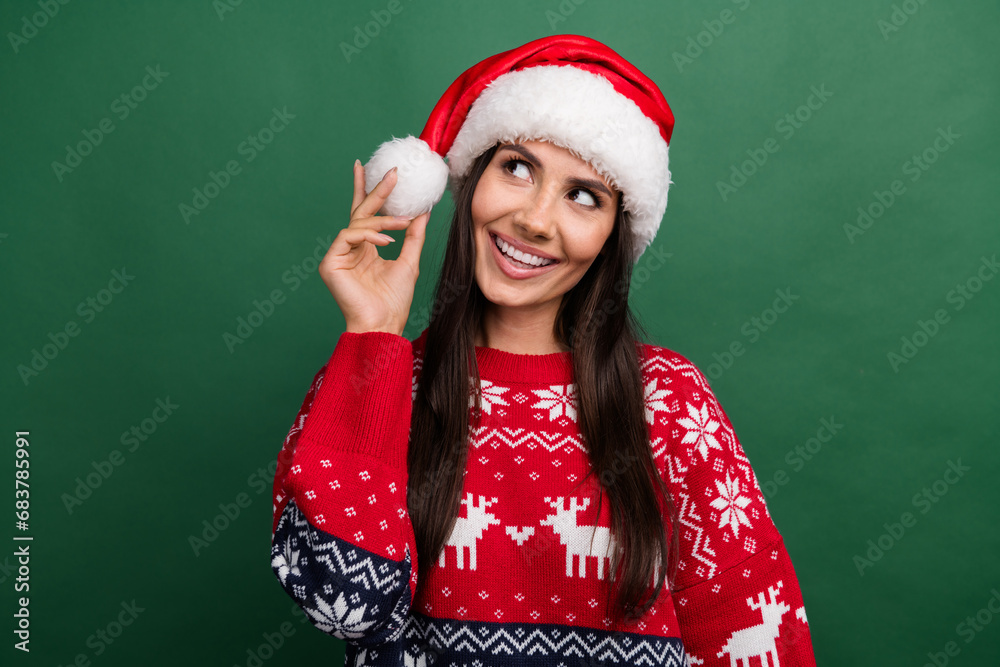 Portrait of gorgeous cheerful person beaming smile arm hold headwear pompom look empty space isolated on green color background Portrait of gorgeous cheerful person beaming smile arm hold headwear pompom look empty space isolated on green color background