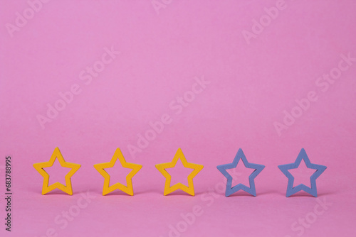 Gold, gray, silver five stars shape on a pink background. Increase rating or ranking, evaluation and classification idea. Three 3 stars. photo