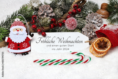 Weihnachtskarte  Label mit Weihnachtsgru   im Schnee mit Weihnachtsmann  Zuckerstange und Zweigen dekoriert. Frohe Weihnachten und einen guten Start ins Jahr 2024.