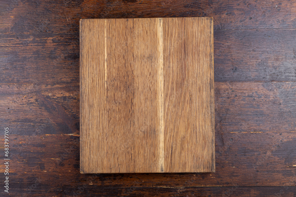 Naklejka premium Kitchen old cutting board on brown background