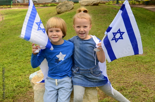 Cute children boy and girl, laughing, hugging with the Israeli flag. Patriotism in kindergarten, preschoolers celebrate Independence Day. Portrait of Israeli children, caring for children photo