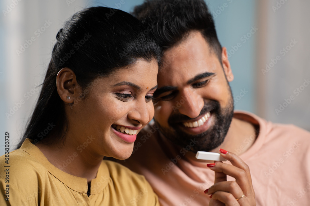 Fototapeta premium Indian couple got excited after seeing positive pregnancy test result at home - concept of expecting baby, good news and affection