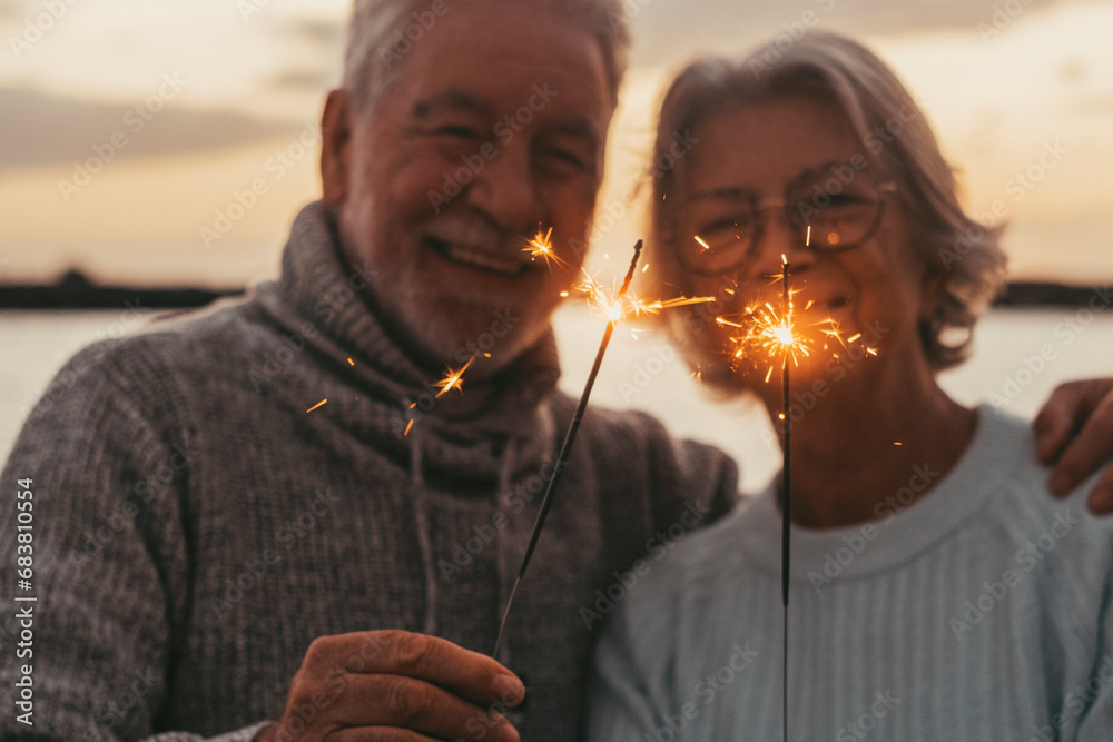 © Daniel - Couple of two old seniors holding sparklers lights at the evening at the beach together enjoying and having fun