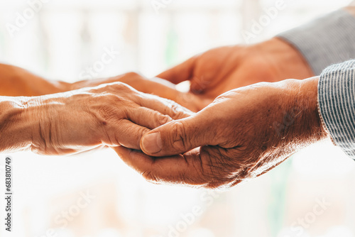 Close up elderly affectionate woman covering wrinkled hands of mature husband, showing love and support at home. Caring middle aged family couple enjoying sincere trustful honest conversation..