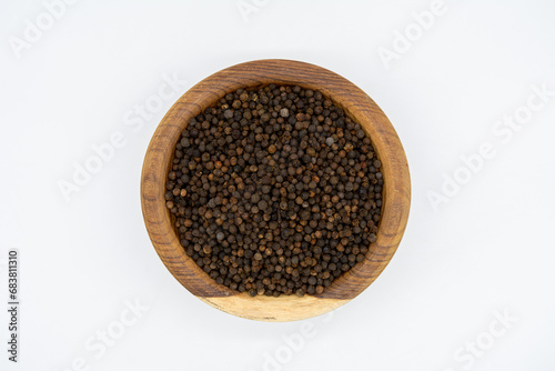 Nigella sativa seeds on a wooden plate isolated on a white background