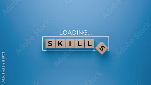 Wooden blocks spelling 'SKILLS' with a loading progress bar on a blue background, skill development and learning concept photo