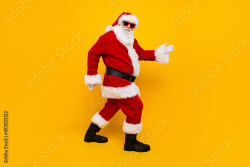 Full body profile portrait of positive eccentric aged santa walking magic new year time isolated on yellow color background