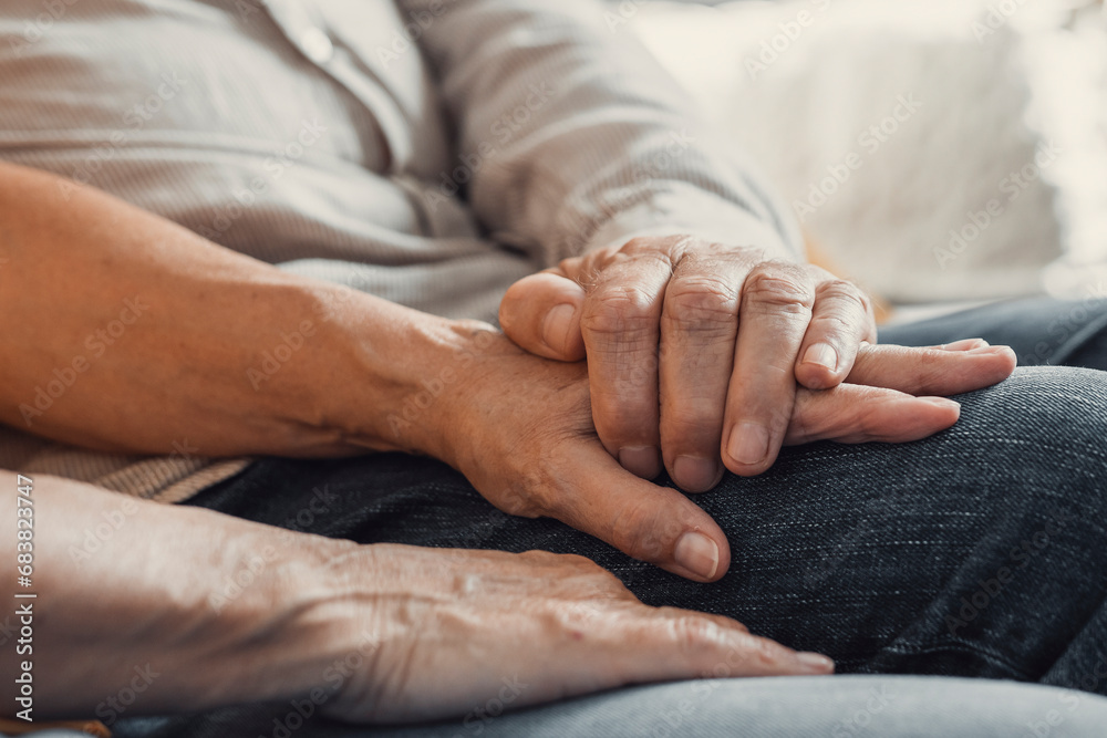 Close up elderly affectionate woman covering wrinkled hands of mature husband, showing love and support at home. Caring middle aged family couple enjoying sincere trustful honest conversation..