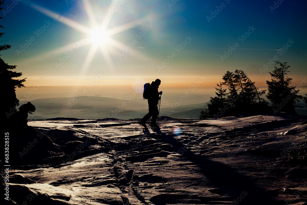 backcountry skier reaching the summit at sunset
