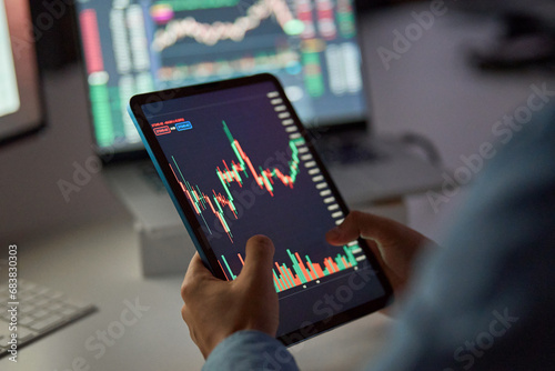 Business man trader broker analyst investor holding tab in hands using digital tablet analyzing stock trade crypto market carts investing finances in stockmarket working in dark night office. Close up photo