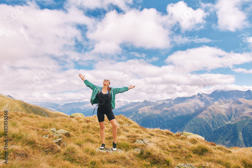 Outdoor portrait of happy young woman hiking in autumn mountains, arms wide open