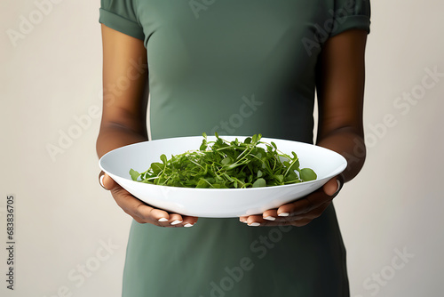A plate of greens in the hands of a young African American woman. Vegetarianism and Veganuary concept