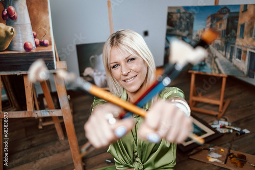 Young blonde woman painter with her brushes