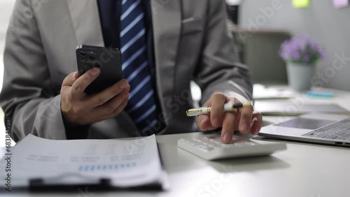 Businessman is checking invoices online by mobile phone and calculating income and expenses and planning finances. photo