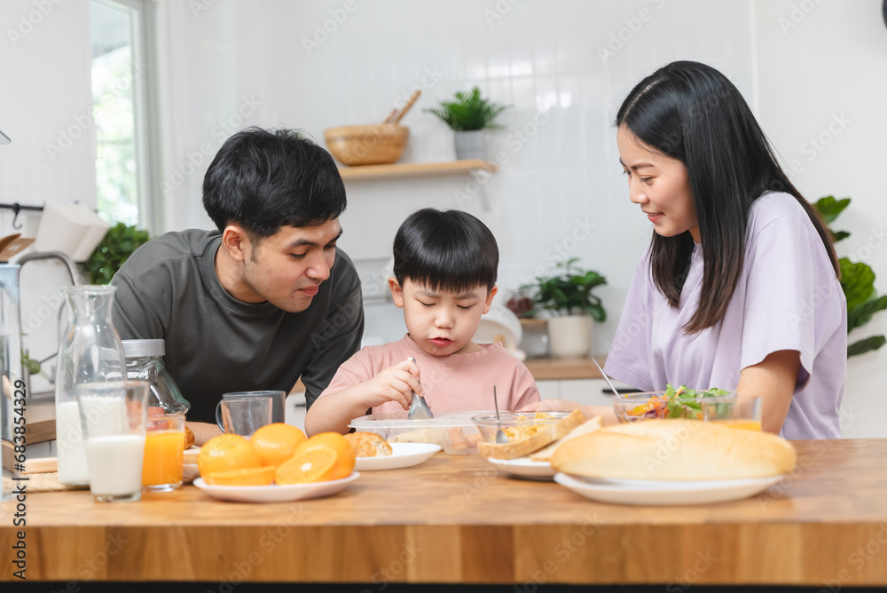 happy family together. Asian parent eating breakfast with little son in the kitchen.