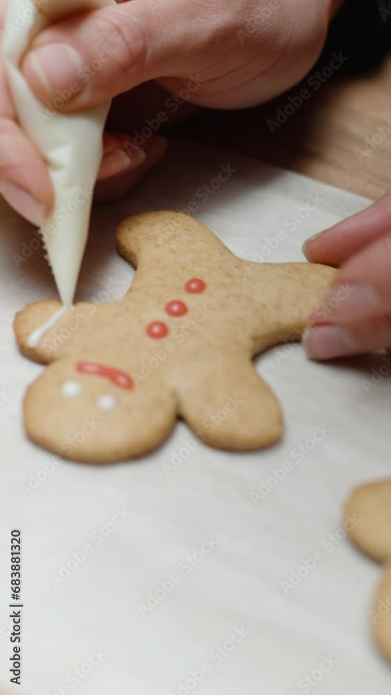 Vertical video. Homemade gingerbread cookies in the shape of little people for Christmas, the woman decorates them with icing. Vertical video. Homemade gingerbread cookies in the shape of little people for Christmas, the woman decorates them with icing.