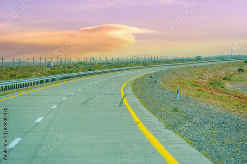Beautiful prairie landscape with a concrete road leading into the distance. Stunning sunset colors lighting up the sky. Serene and peaceful scene  1