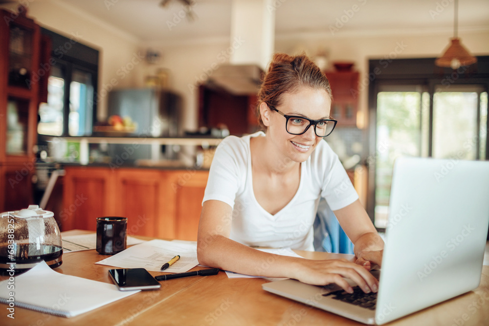 Smiling young woman doing financials at home Smiling young woman doing financials at home