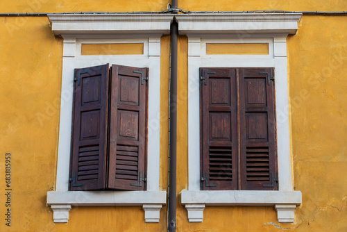 Persiane in legno sulla facciata gialla della vecchia casa, Palmanova, Italia.