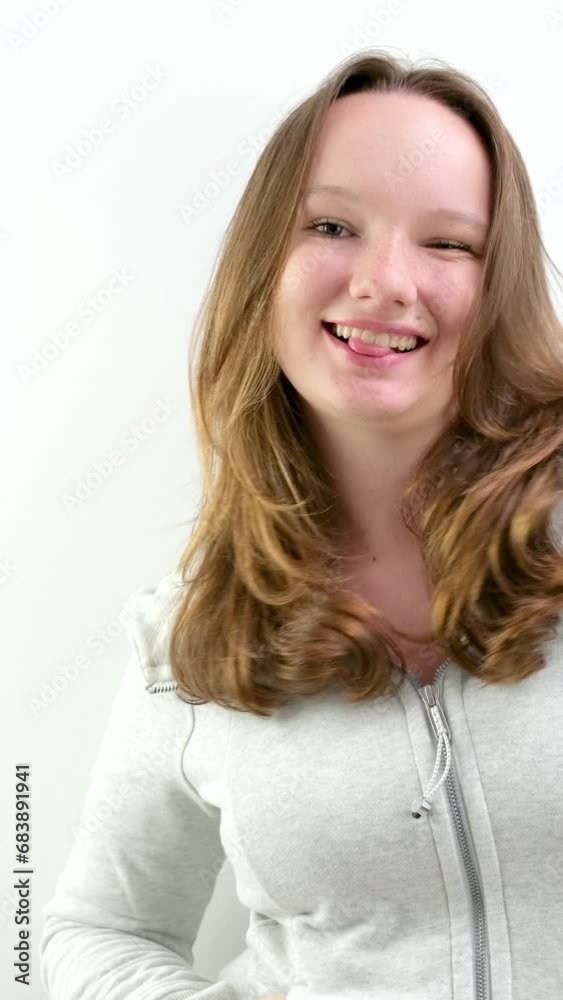 girl flirts hands in pockets sports gray sweater show tongue wrinkle nose dance on white background adolescence teenage girl. young woman girl flirts hands in pockets sports gray sweater show tongue wrinkle nose dance on white background adolescence teenage girl. young woman