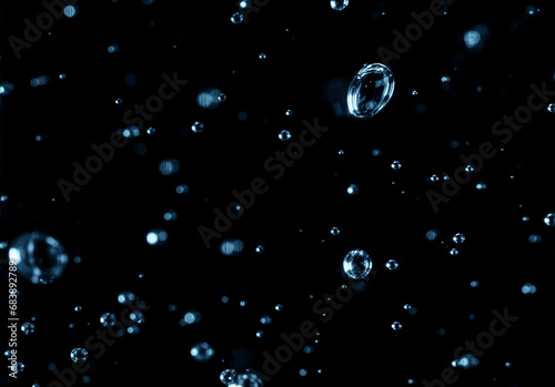 Small air bubbles with blue tint in a clear liquid. Air bubbles on a black background. Transparent liquid with bubbles