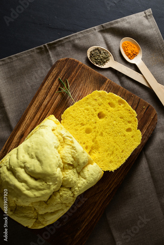 Fresly baked, crustly bread, flavored with turmeric and rosemary, on a wooden chopping board
