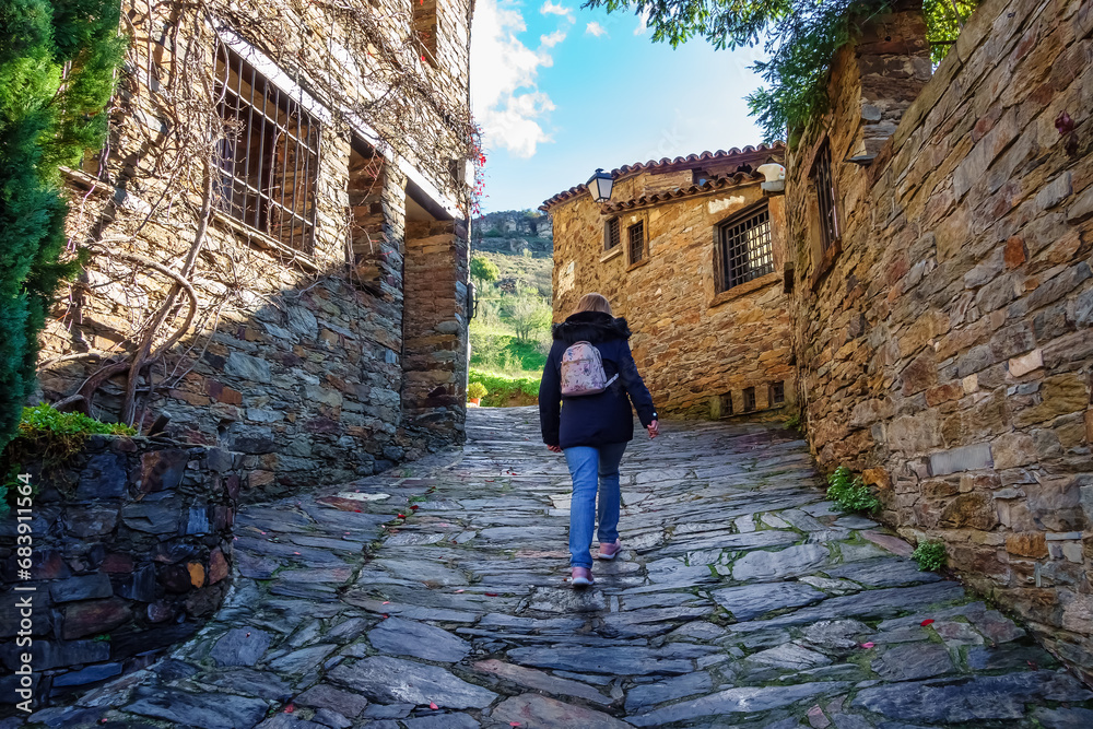 Tourist woman strolling through the cobbled streets of the old town of Patones de Arriba, Madrid.