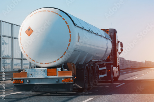 Petroleum Cargo Truck Driving On The Highway Hauling Oil Products. Fuel Delivery Transportation And Logistics Concept On A Sunny Summer Evening. Compressed Gas Carrier Truck Rear View On A Highway. photo