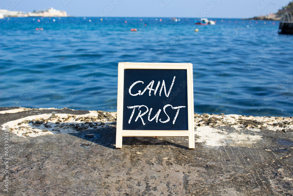 Gain trust symbol. Gain trust on black chalk blackboard. Beautiful sea background. Business and Gain trust concept. Copy space.