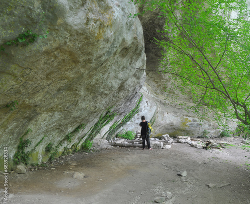 A woman stands near a rock wall in Alimovom grote. Crimea