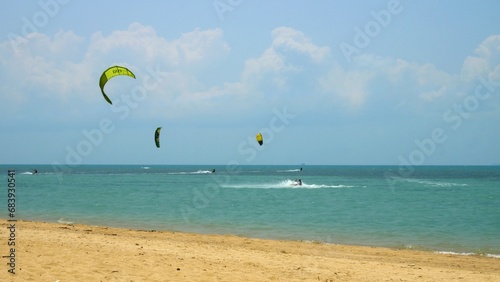 Kite-surfing race slow motion flying on sky during sunset mountain background. Sailboard beach relax weekends. Kite surfing race over sea summer vacation and holiday. Sports water concept Kitesurfing.