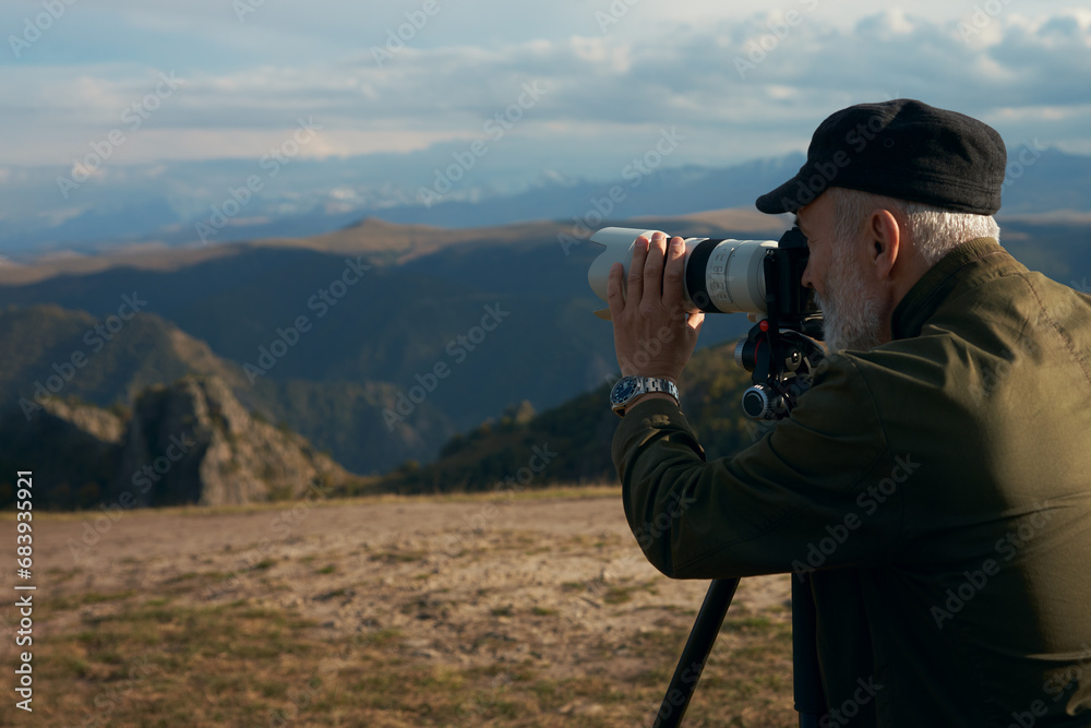 Photography of a mountain landscape with a long lens. Photographer with a camera fixed on a tripod.