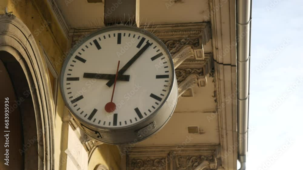 Large clock face with arrows at railroad station. Red second hand moves