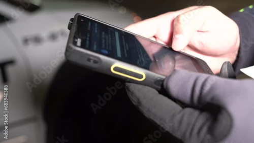 A security guard is conducting a circle check on his patrol fleet vehicle car with a digital report system on his phone.
