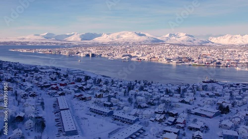 Soaring above the snow covered landscape of Norwegian town of Troms in winter season. Picturesque coastal scenery, icy fjords and the unique blend of urban life and Arctic wilderness. photo