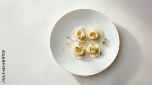  a white plate topped with ravioli and garnished with green garnish on top of a white table.