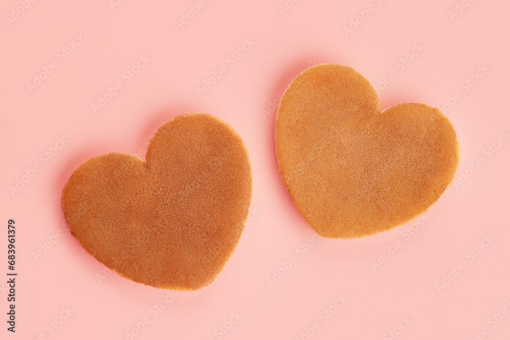 Fototapeta premium Close up top view of two heart shaped pancakes on the pink background