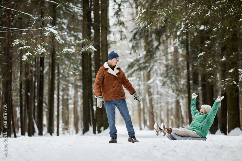 Naklejka premium Joyful senior couple spending together in winter forest