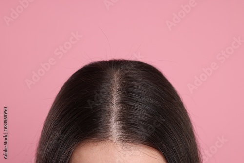 Woman with healthy dark hair on pink background, closeup photo