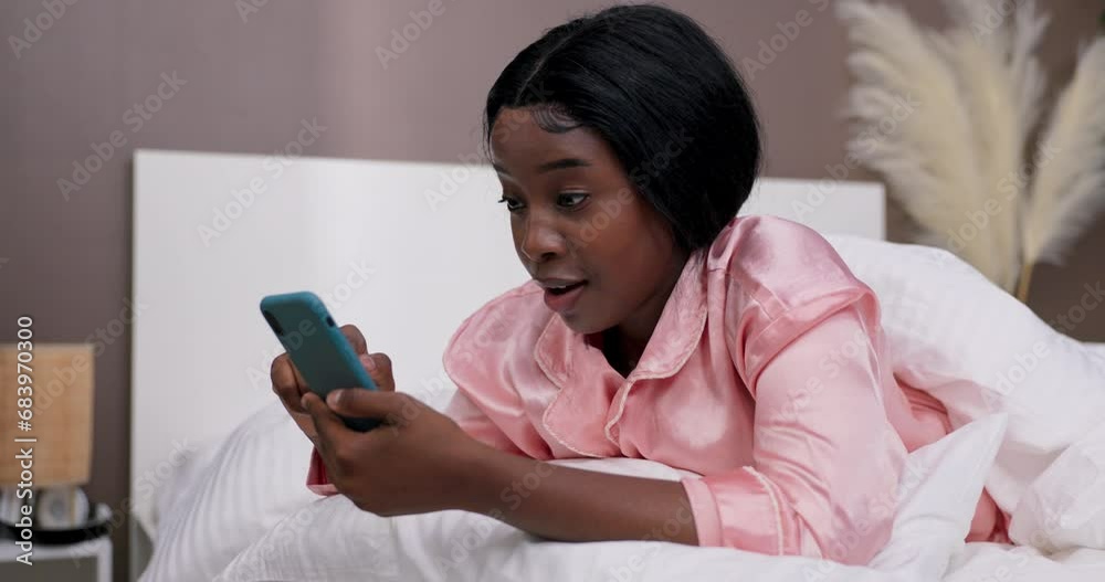 A woman browses social media on phone after waking up. She is surprised, pdexcited by the information she has read on the Internet, scrolling social networks with delight. A woman browses social media on phone after waking up. She is surprised, pdexcited by the information she has read on the Internet, scrolling social networks with delight.