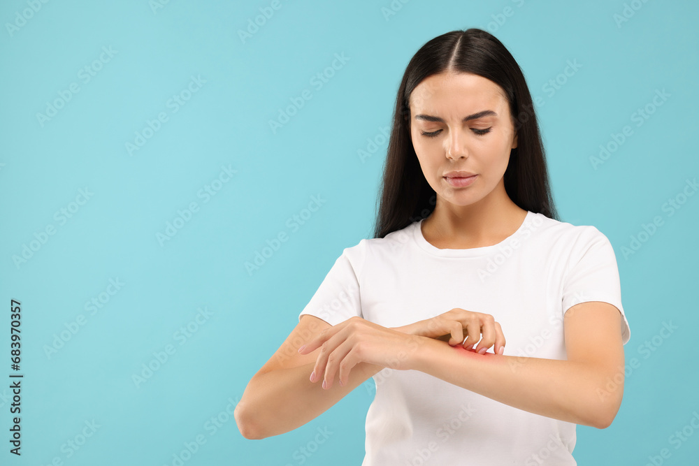 Suffering from allergy. Young woman scratching her arm on light blue background. Space for text Suffering from allergy. Young woman scratching her arm on light blue background. Space for text