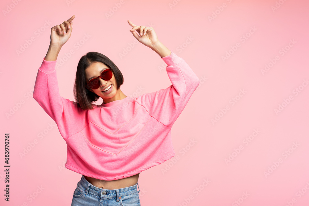 Portrait of young Asian woman holding hands up pointing fingers wearing sunglasses, shopping concept Portrait of young Asian woman holding hands up pointing fingers wearing sunglasses, shopping concept