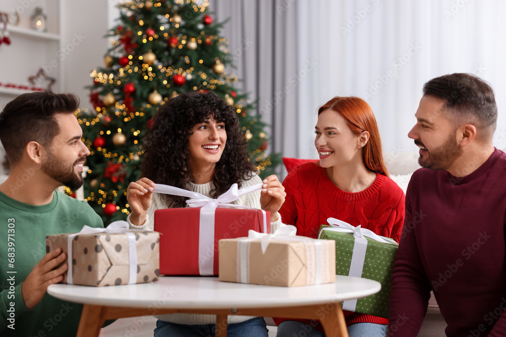 Christmas celebration in circle of friends. Happy woman opening gift at home Christmas celebration in circle of friends. Happy woman opening gift at home