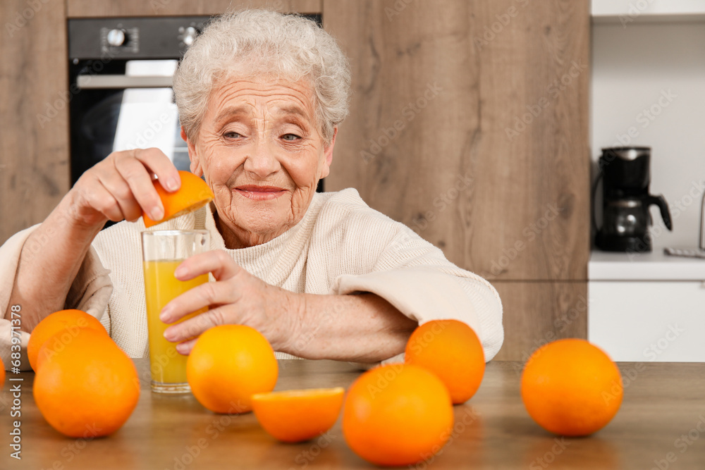 Senior woman squeezing orange juice into glass in kitchen Senior woman squeezing orange juice into glass in kitchen