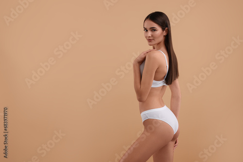 Young woman in stylish white bikini on beige background. Space for text
