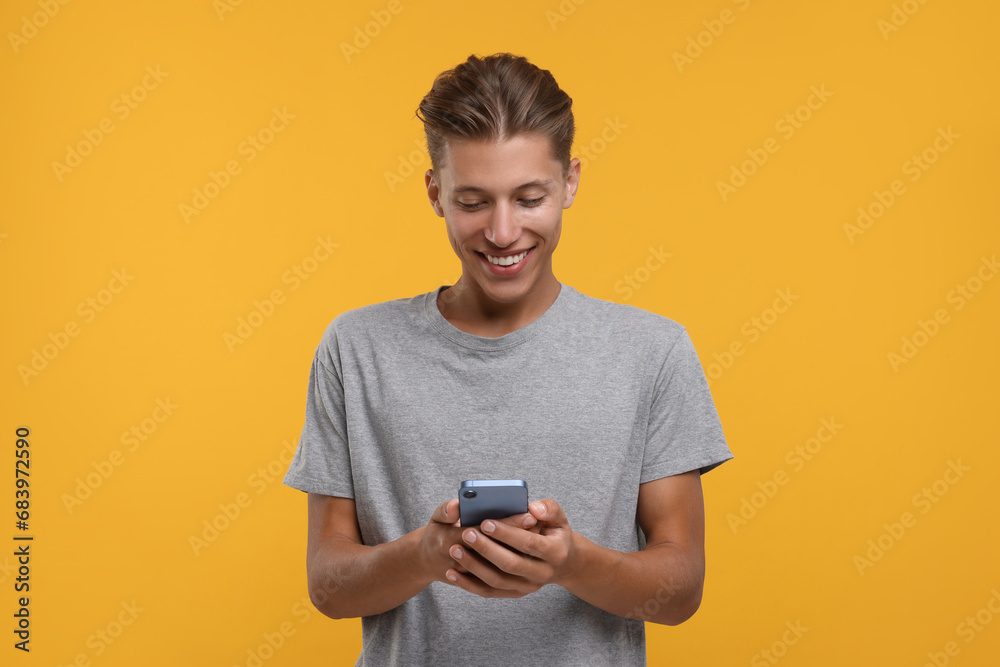Happy man using smartphone on orange background Happy man using smartphone on orange background