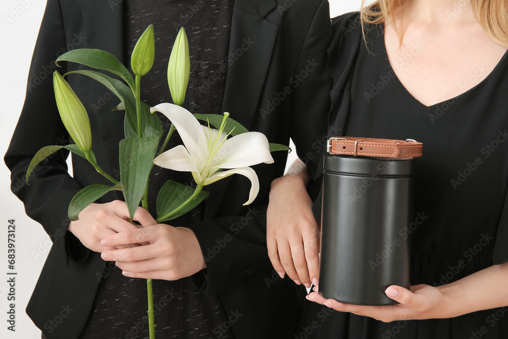 Women with mortuary urn, dog collar and lily flowers, closeup. Pet funeral - obrazy, fototapety, plakaty 
