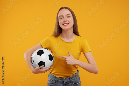 Happy sports fan with ball on yellow background © New Africa