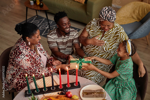 Happy parents giving daughter Zawadi, gift for Kwanzaa celebration photo